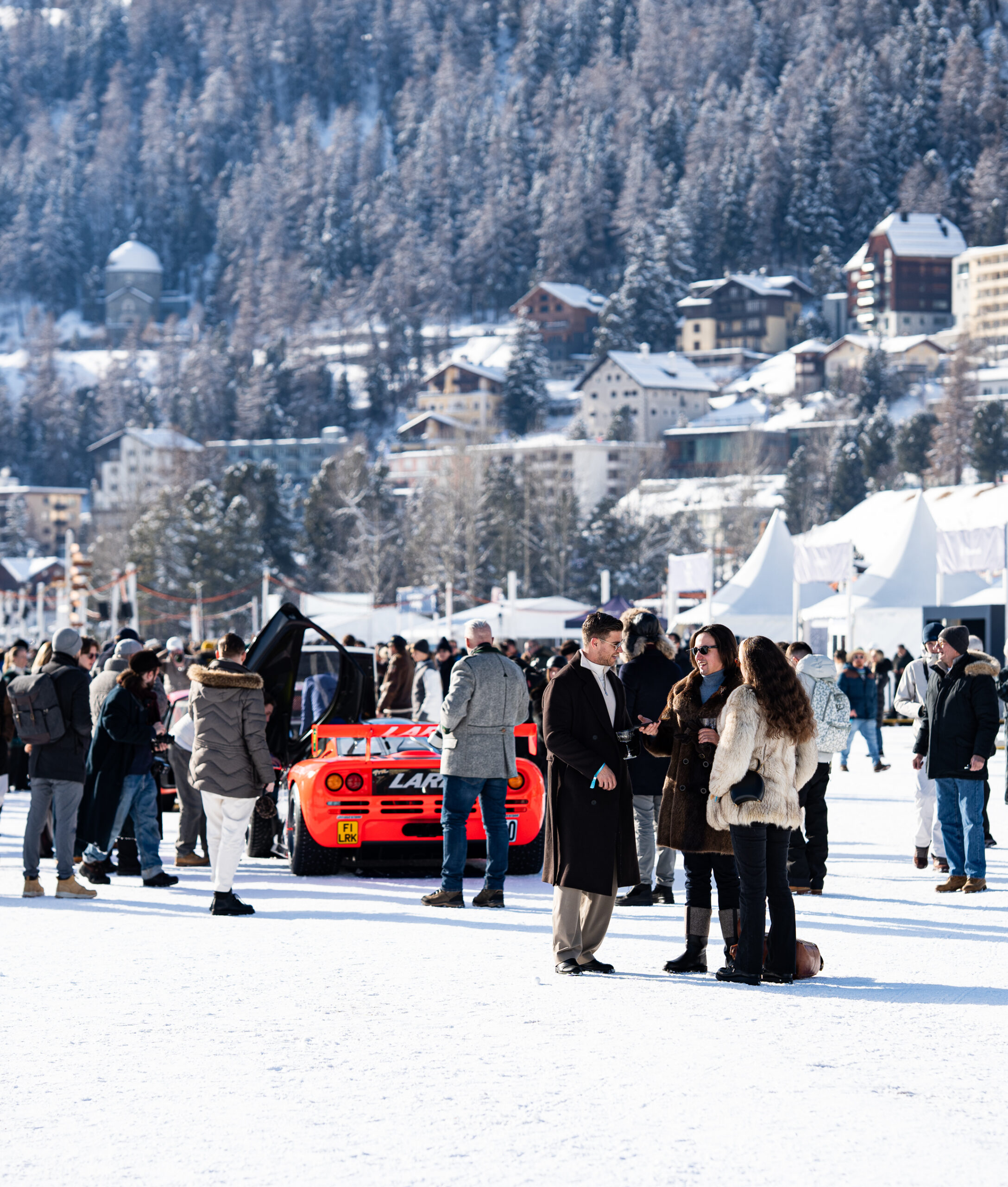 Viele Gäste und Rennwagen bei einem Premium-Event im Schnee vor Bergkulisse