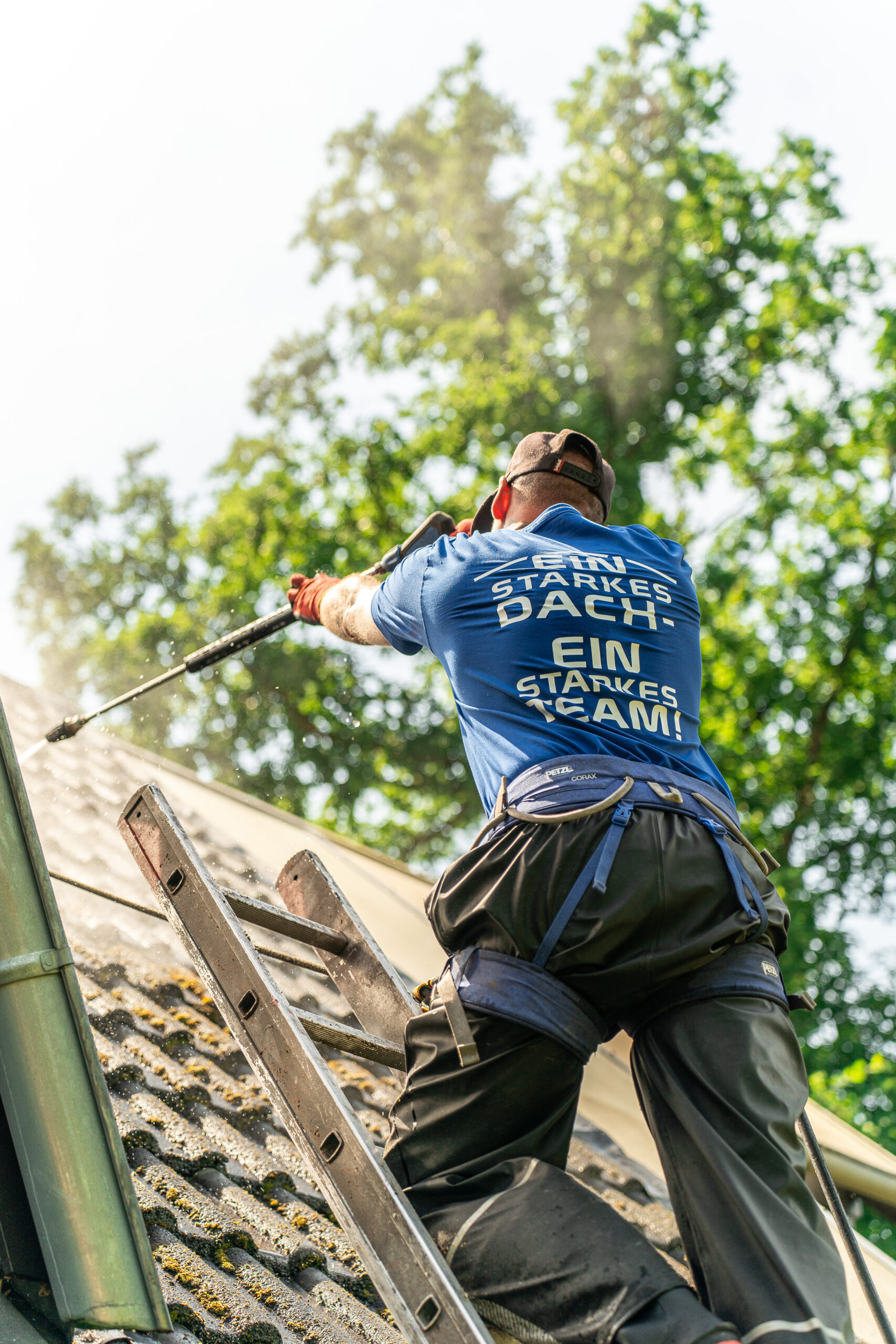 Dachdecker reinigt ein Ziegeldach mit dem Hochdruckreiniger, Handwerksreportage für Familienbetriebe in Lübeck